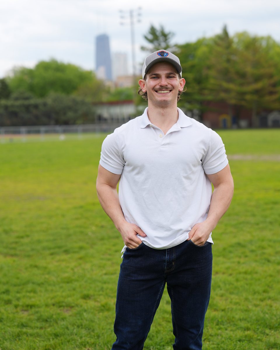 CJ Friedlander smiling in a park with the city skyline behind him