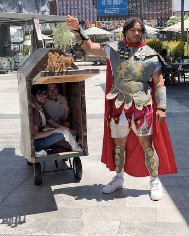 The crew hidden inside a homemade Trojan horse cart, led by a performer in Greek soldier costume outside a theater